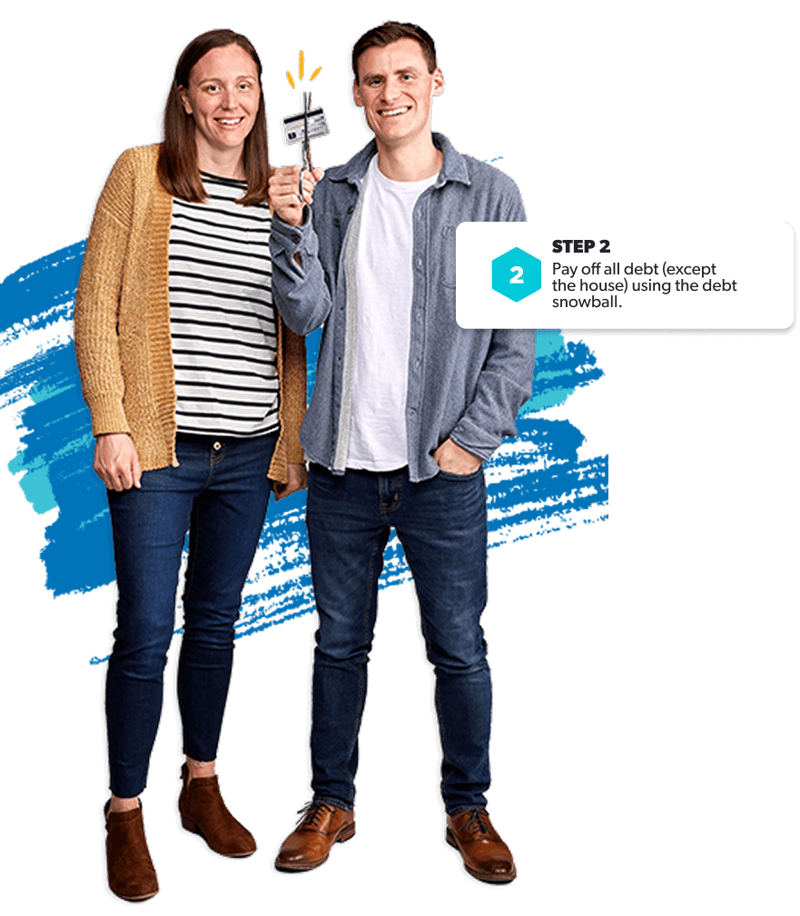Couple smiles as they cut up a credit card—ready to ditch debt and start the debt snowball.